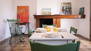 Un coin repas avec une table dressée pour quatre personnes, des chaises vertes et des œuvres d’art accrochées aux murs.