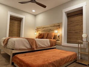 A bedroom with a bed, a bedside table with a lamp, a ceiling fan, and a window with blinds. - Sunset Lake Cottage at Mammoth Cave (Mammoth Cave)
