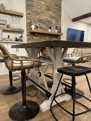 A rustic bar area with a stone wall, wooden shelves, and wicker chairs. - Sunset Lake Cottage at Mammoth Cave (Mammoth Cave)