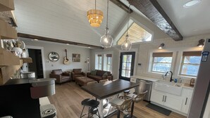 A spacious kitchen with a central island, wooden flooring, and a high ceiling with exposed beams. - Sunset Lake Cottage at Mammoth Cave (Mammoth Cave)