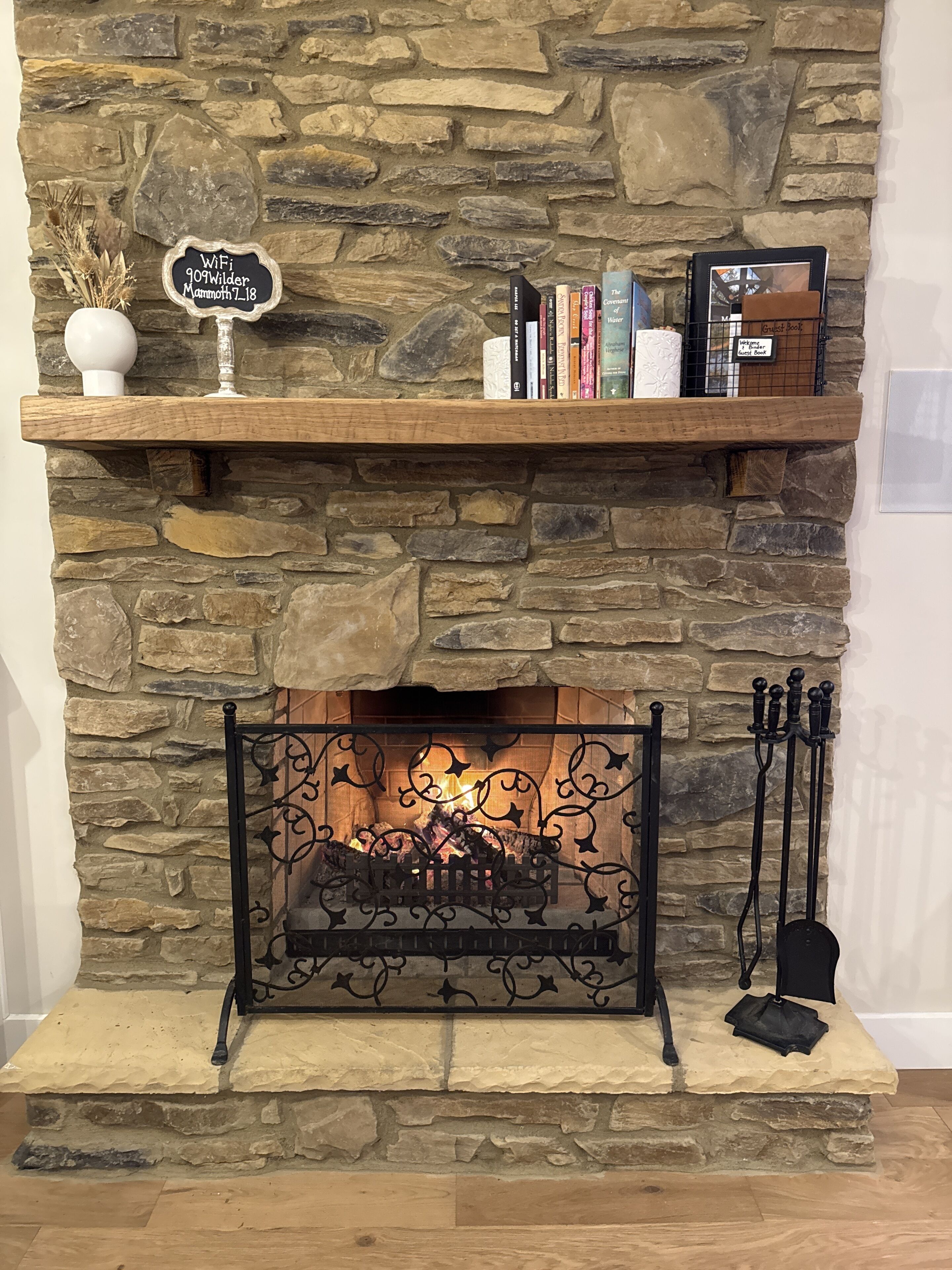 A stone fireplace with a wooden shelf above it, holding books and a sign indicating WiFi availability.