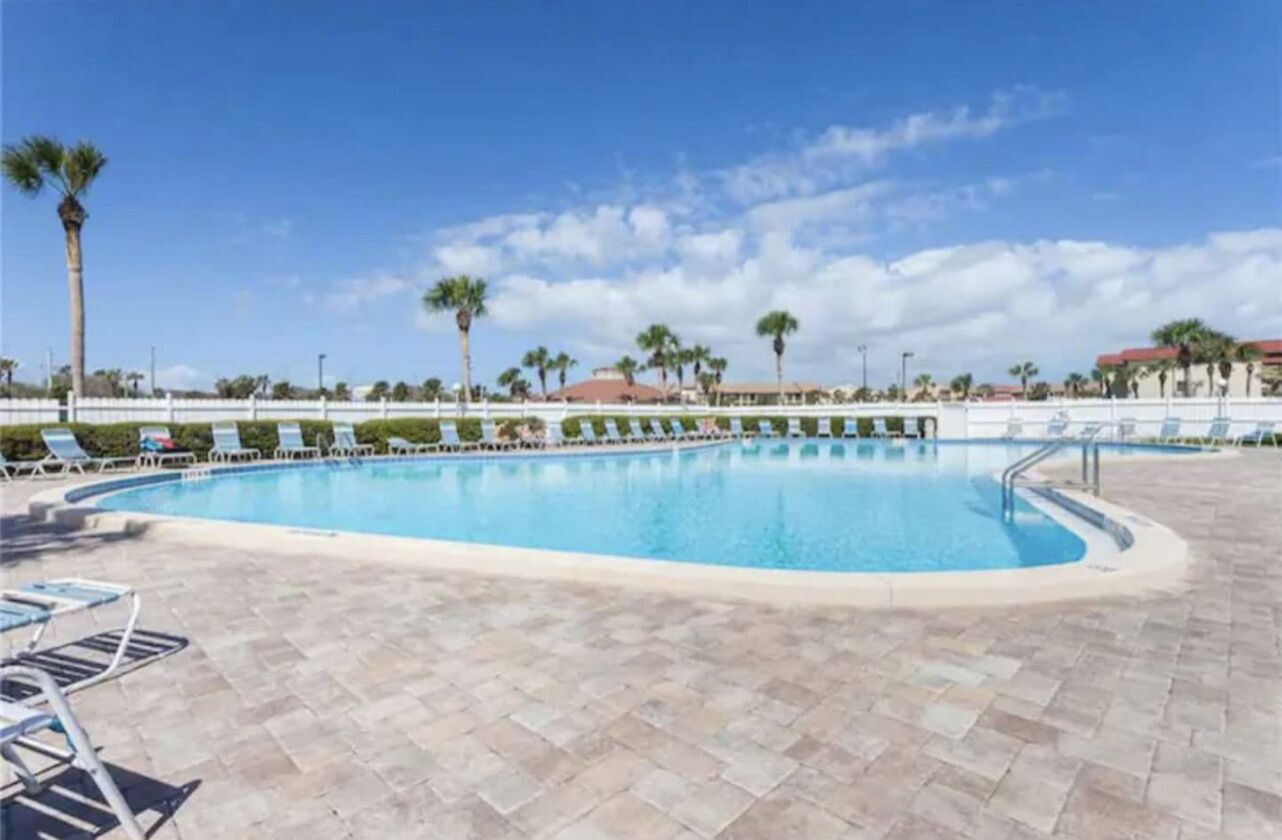 Une piscine avec des chaises longues et des palmiers.