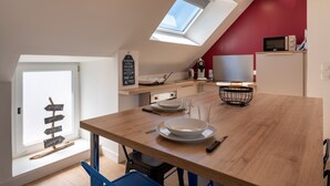 A modern kitchen with a skylight, a dining table, and a red accent wall.