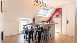 A modern kitchen with a skylight, bar stools, and a microwave on the counter.