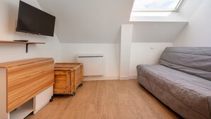 Una habitación con televisión, muebles de madera, un sofá y un tragaluz.