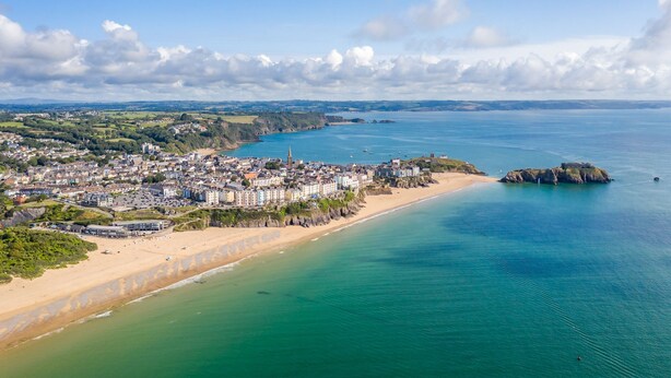 An aerial view of a coastal town with a beach, buildings, and a rocky outcrop. - Stunning Seafront Apartment in the heart of Tenby (Tenby)