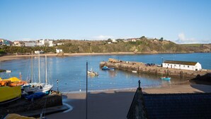 A coastal harbor with boats docked, a sandy beach, and buildings in the background. - Stunning Seafront Apartment in the heart of Tenby (Tenby)