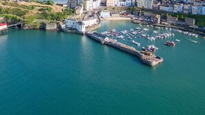 An aerial view of a coastal town with a marina, a lighthouse, and a fortified structure. - Stunning Seafront Apartment in the heart of Tenby (Tenby)