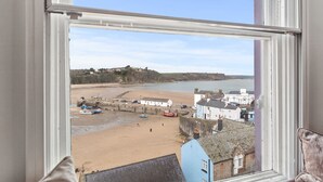 A coastal town view from a window, including a sandy beach, boats, and buildings. - Stunning Seafront Apartment in the heart of Tenby (Tenby)
