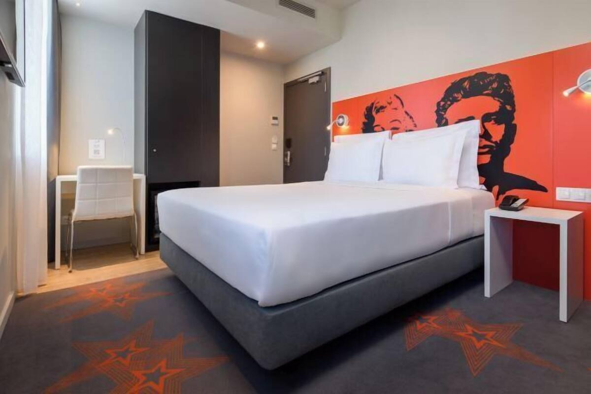 Una habitación de hotel moderna con una cama grande, un escritorio y una silla.