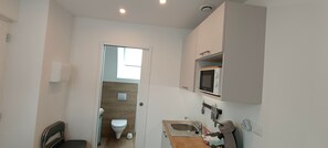 Een kleine badkamer met toilet, wastafel en een magnetron erboven.