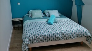 Un dormitorio con cama, almohadas, una mesita y un estante en la pared.