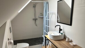 Un baño moderno con inodoro, lavabo, ducha y tocador de madera.