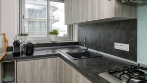 Moderni keittiö, jossa on sisäänrakennettu kaasuliesi, pesuallas ja ikkuna, josta on näkymä rakennukseen.