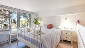 Een slaapkamer met een bed, nachtkastjes, een raam met uitzicht en een plant in een pot.