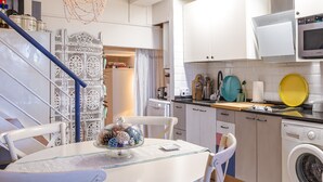 Een moderne keuken met witte kasten, een wasmachine en een eethoek met een tafel en stoelen.