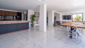 A spacious modern kitchen with a marble floor, a dining area with a wooden table and clear chairs, and a large potted plant. - Holiday Home 'Villa Nina' with Mountain View, Wi-Fi and Air Conditioning (Mirepeisset)