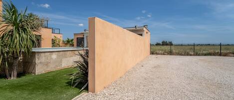 A modern building with a flat roof, a gravel driveway, and a well-maintained lawn.