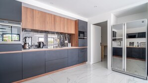 A modern kitchen with dark cabinetry, a wooden countertop, and a marble backsplash. - Holiday Home 'Villa Nina' with Mountain View, Wi-Fi and Air Conditioning (Mirepeisset)