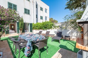 Un patio con una mesa de comedor, sillas y una mesita con lámpara.