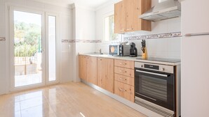 Una cocina con armarios de madera, horno empotrado y cafetera.