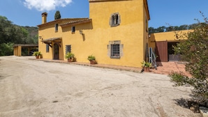A yellow building with a tiled roof, potted plants, and a clear sky. - Country House 'Can Marc' with Mountain View, Private Pool and Wi-Fi (Dosrius)