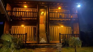 A two-story building with a balcony on each floor, a staircase leading to the entrance, and a sign with directional information. - Altos da Lagoa-praia do Rosa,ibiraquera Studio 1 Para Casais Calmo e Tranquilo (imbituba)