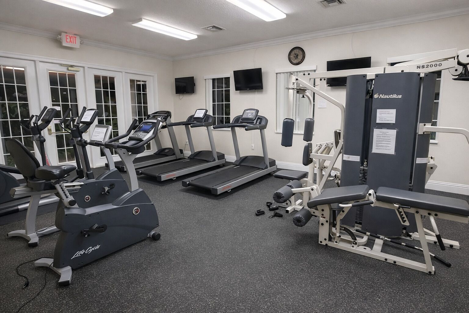 A gym with treadmills, an elliptical, and Nautilus weight machines.