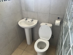 A bathroom with a sink, toilet, and a glass shower enclosure. - Sunset Plaza Apartments 4 (Victoria)
