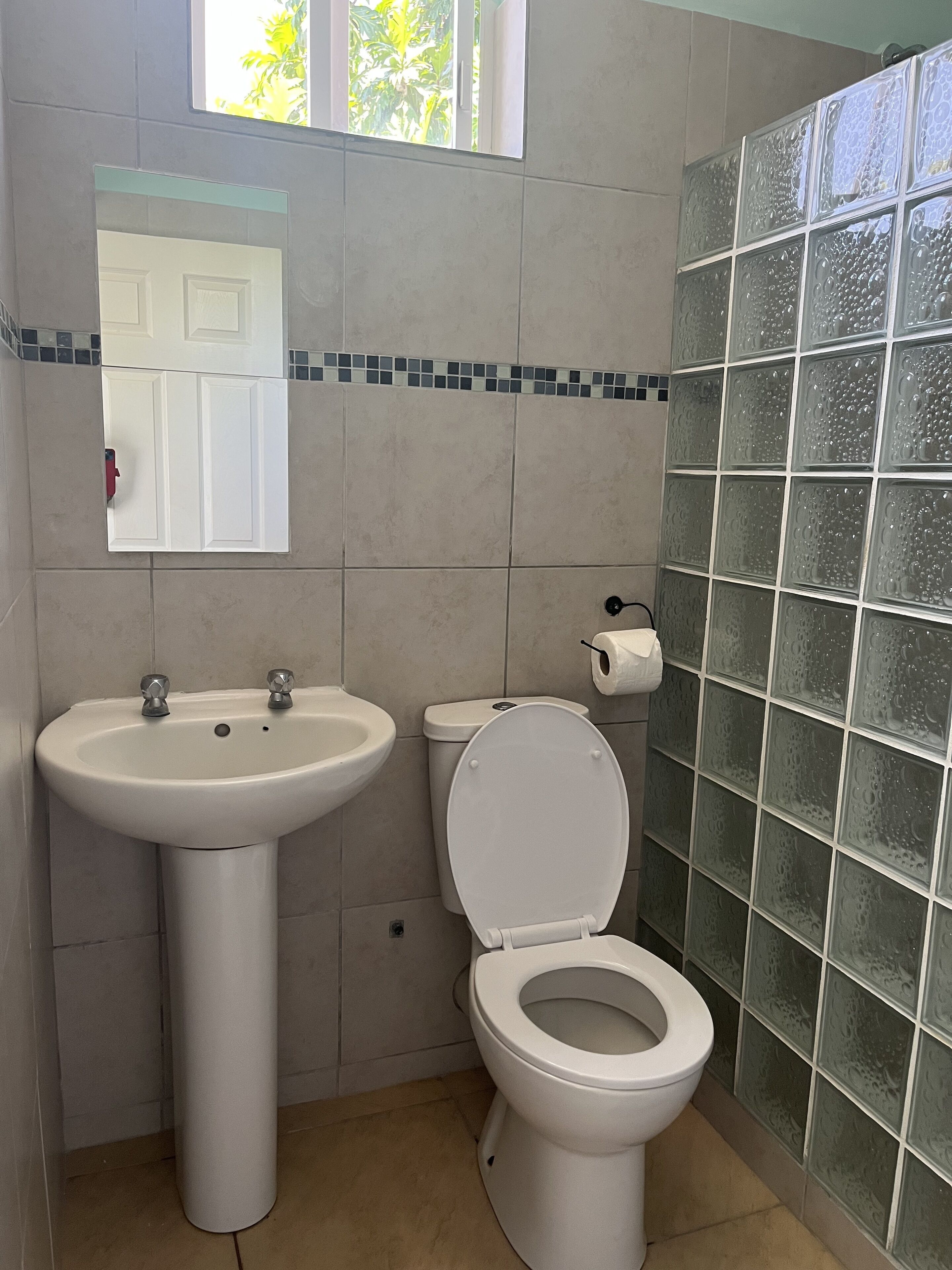 A bathroom with a sink, toilet, and a window.