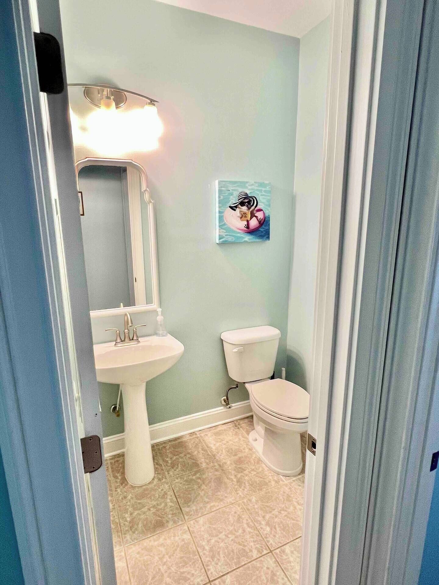 Une salle de bain équipée d’un lavabo, de toilettes et d’un luminaire fixé au mur.