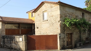 A stone building with a tiled roof, a wooden door, and a window.