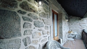 A stone-walled room with a wicker chair and a small table.