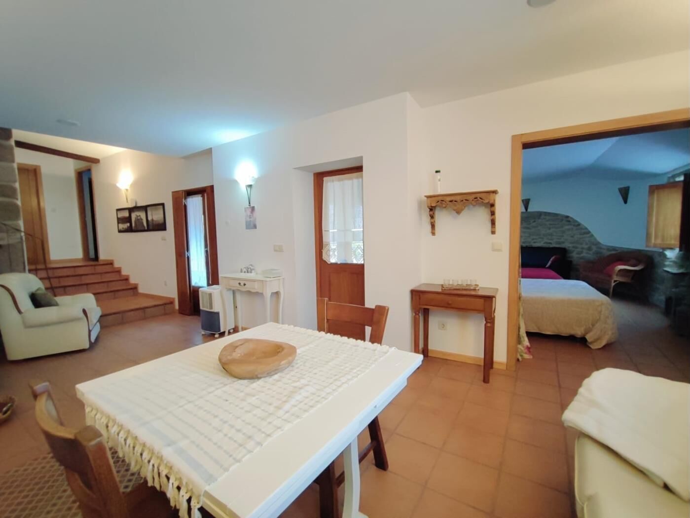 Une pièce confortable avec une table à manger, un canapé et un lit. Un escalier mène à une autre pièce.