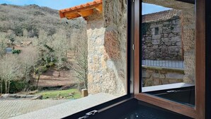 Un edificio de piedra con techo de tejas, pared de piedra y ventana con marco de madera.