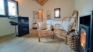 Una habitación acogedora con techo de madera, una mesa de comedor con sillas, chimenea y una zona de bar.