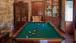 A pool table with balls, a chair, a bookshelf, and a stone wall. - Quinta Vila Nova | Apartamento das Camélias | Agrotourism | Rural Environment (Monção)
