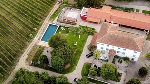 An aerial view of a property with a swimming pool, a large building with a red-tiled roof, and a vineyard. - Quinta Vila Nova | Apartamento das Camélias | Agrotourism | Rural Environment (Monção)