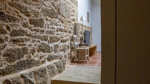 Un escalier en pierre mène à une pièce où se trouvent un bureau en bois, une chaise et une lampe.