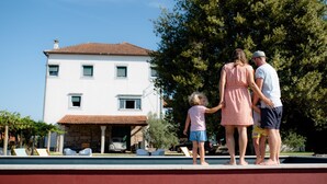 Eine Familie steht vor einem weißen Gebäude mit einem Ziegeldach, einer Steinfassade und einer Garage.