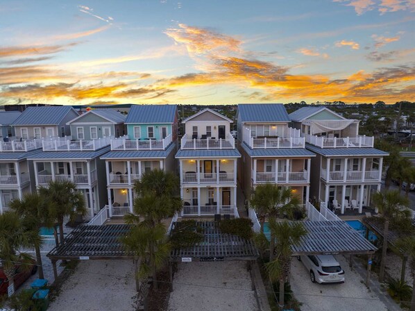 A row of beachfront bungalows with balconies, a pool, and a beach view. - 4806 Hispaniola St. 3 Kings - 4 Twins - Private Heated Pool! 2 Minute Walk to the Sand! (Panama City Beach)