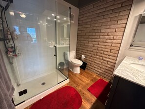 Bathroom features a glass-enclosed shower, toilet, and sink.