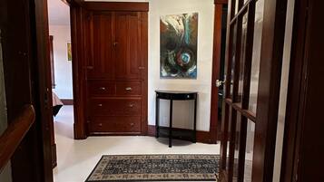 Un couloir avec une porte en bois, une table noire et un tableau accroché au mur.