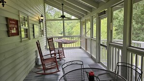 A covered porch with wooden railings, a table, chairs, and a hammock. - Cardinal Nest -Mountain views, babbling stream, fields to play in, privacy! (Blairsville)