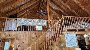 Ein Holzinnenraum mit Treppe, Deckenventilator und einer Uhr an der Wand.