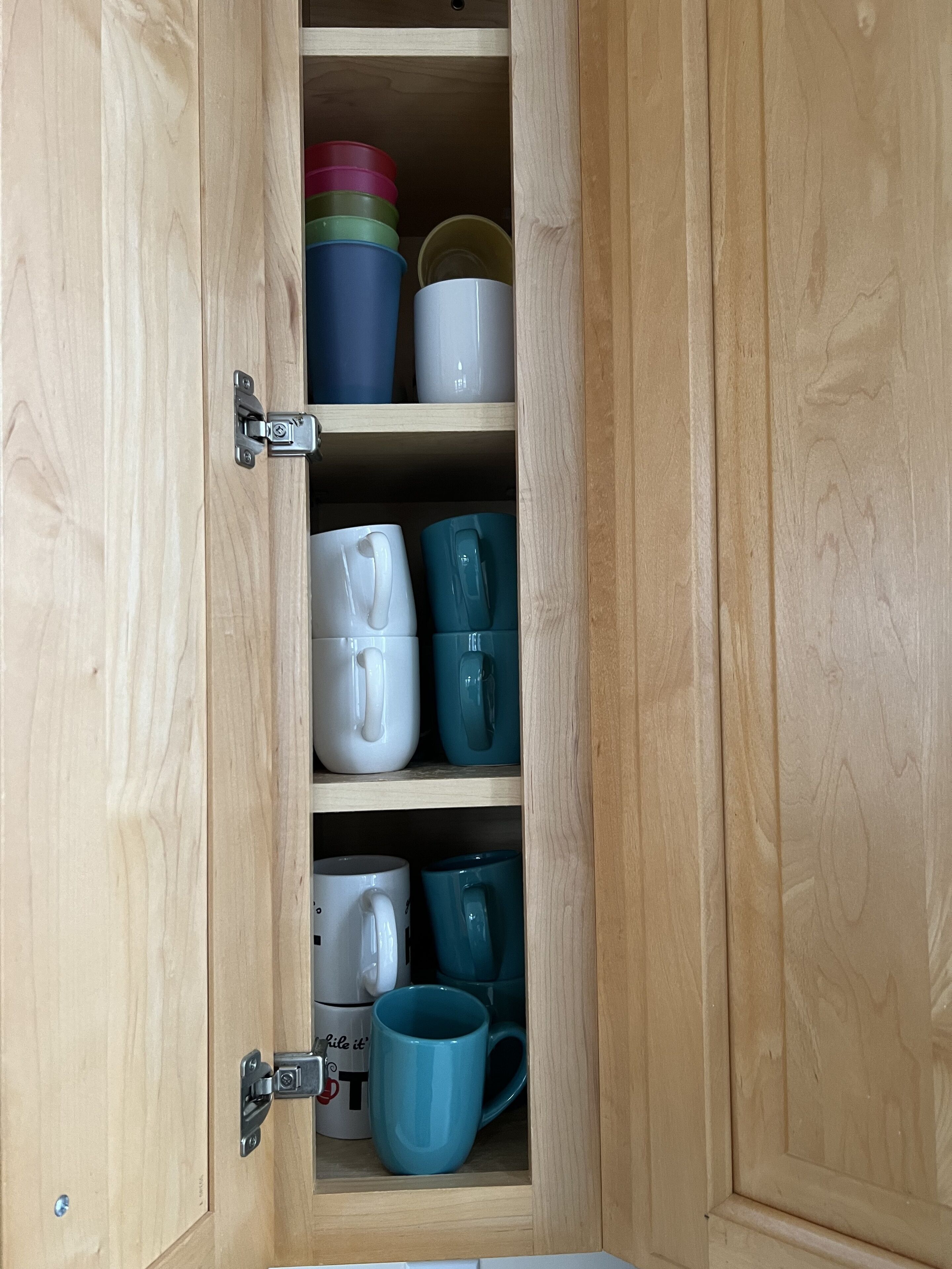 Un armari de fusta amb diverses prestatgeries que conté diverses tasses i recipients.