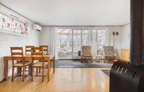 A room with a wooden dining table and chairs, a large window with a view, and a black radiator.