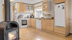 Een keuken met houten kasten, een fornuis, een koelkast en een vaatwasser.