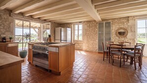 A kitchen with a central island, wooden cabinets, a built-in oven, and a stone wall.