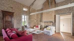 A spacious living room with stone walls, a wooden ceiling, and a red sofa.